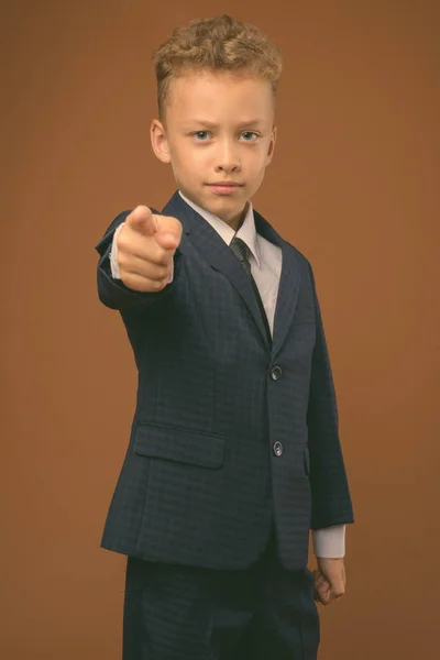 Jonge jongen als zakenman tegen bruine achtergrond — Stockfoto