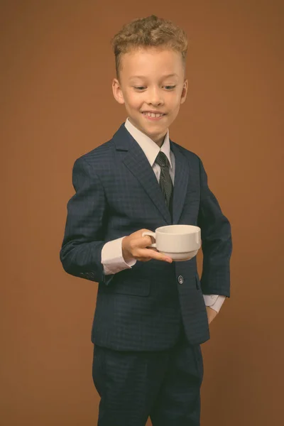 Мальчик как бизнесмен на коричневом фоне — стоковое фото