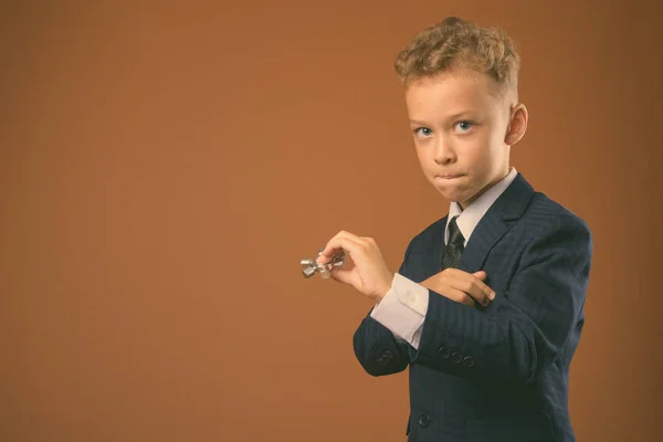 Мальчик как бизнесмен на коричневом фоне — стоковое фото