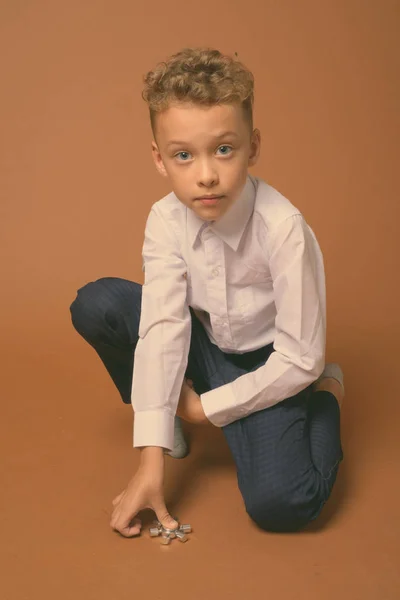 Mladý chlapec jako podnikatel na hnědém pozadí — Stock fotografie