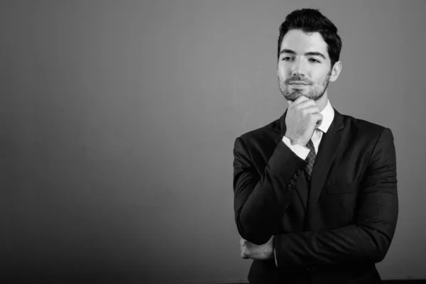 Jovem empresário bonito em terno contra fundo cinza — Fotografia de Stock