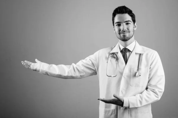 Portret van jonge knappe man arts tegen grijze achtergrond — Stockfoto