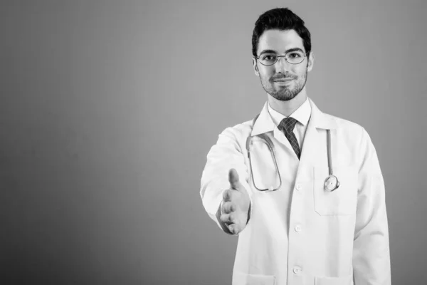 Portrait of young handsome man doctor against gray background — Stock Photo, Image