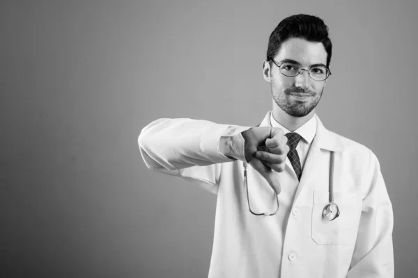 Retrato de jovem homem bonito médico contra fundo cinza — Fotografia de Stock