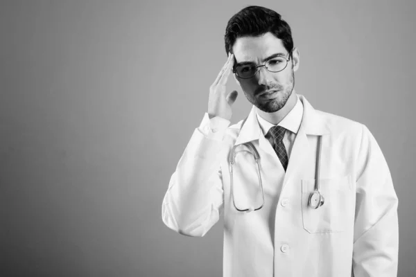 Retrato de jovem homem bonito médico contra fundo cinza — Fotografia de Stock