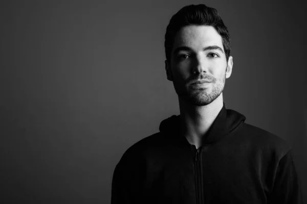 Young handsome man wearing hoodie against gray background — Stock Photo, Image