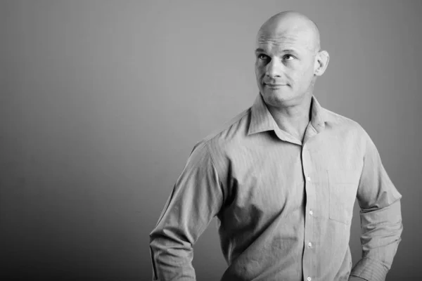 Portrait of bald businessman against gray background
