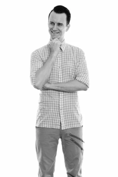 Studio shot of young happy man smiling and standing while thinking — Stock Photo, Image