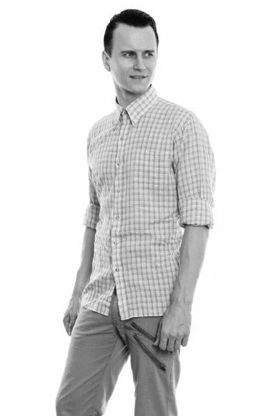 Studio shot of young handsome man standing and thinking while looking back — Stock Photo, Image