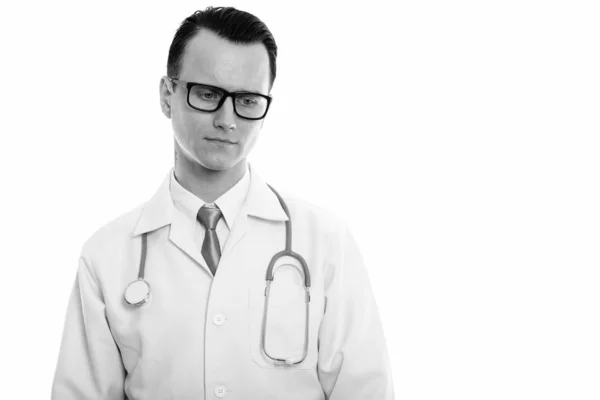 Studio shot of young sad man doctor thinking while looking down — Stock Photo, Image