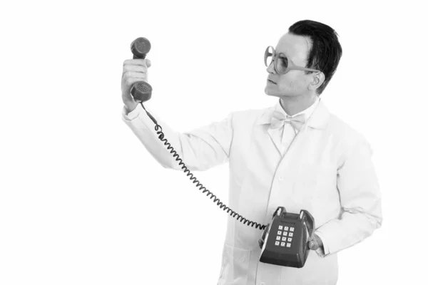 Studio shot van gekke jongeman arts houden en kijken naar oude telefoon — Stockfoto