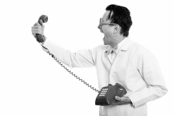 Profiel te bekijken van gekke jongeman arts holding en schreeuwen bij oude telefoon — Stockfoto