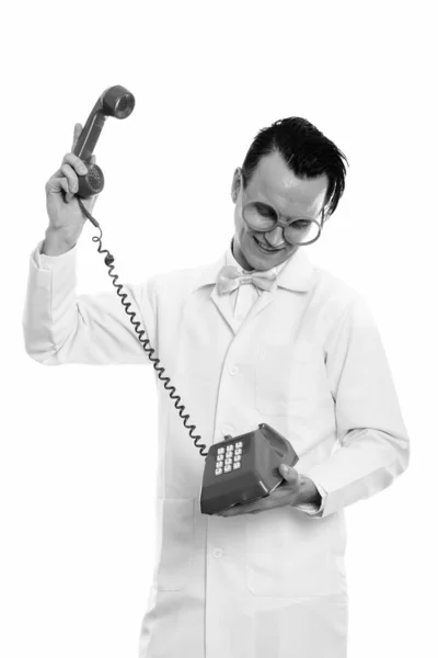 Studio shot of happy crazy man doctor souriant tout en soulevant vieux téléphone — Photo