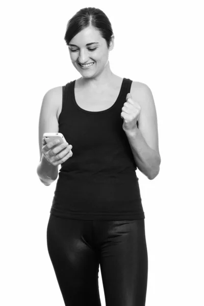 Feliz hermosa mujer sonriendo mientras sostiene el teléfono móvil buscando motivado —  Fotos de Stock