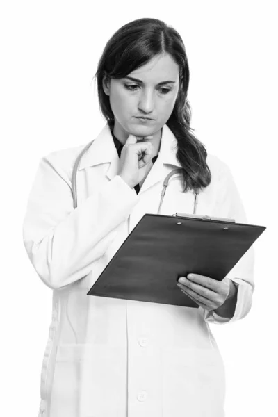 Estudio de la foto de la hermosa mujer médico leyendo en el portapapeles mientras pensaba —  Fotos de Stock