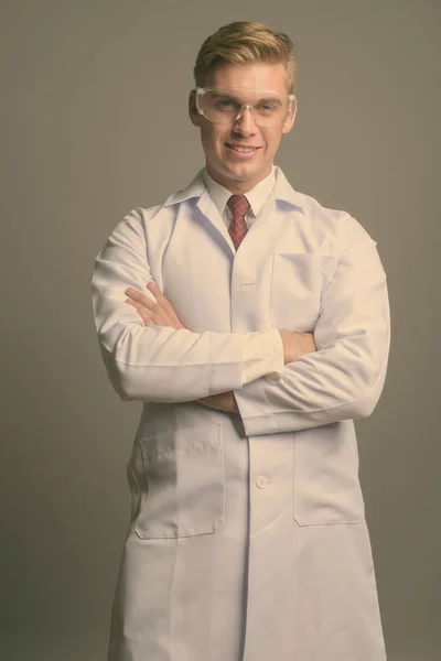 Jeune beau docteur homme aux cheveux blonds sur fond gris — Photo