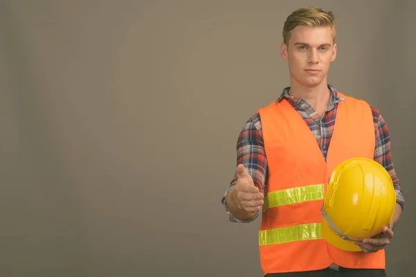 Ung stilig man byggnadsarbetare med blont hår mot grå bakgrund — Stockfoto