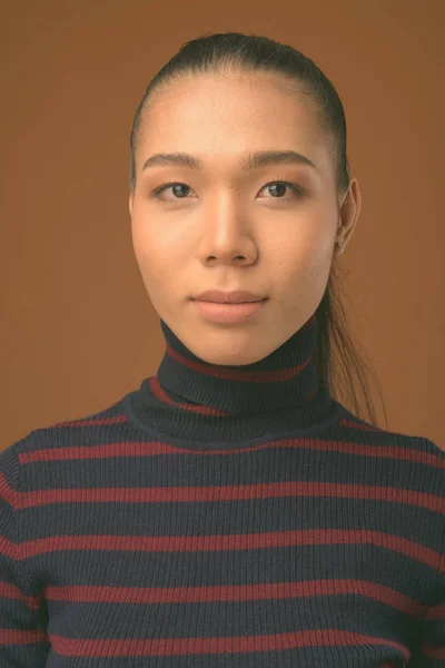 Joven hermosa mujer transgénero asiática contra fondo marrón —  Fotos de Stock