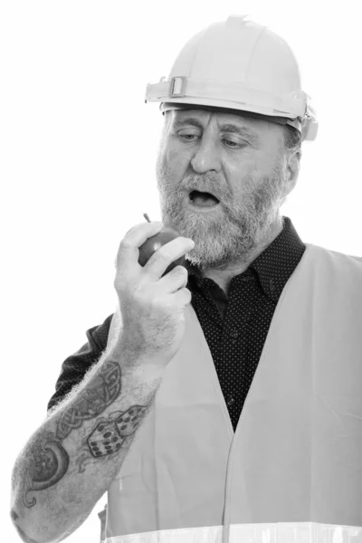 Mature bearded man construction worker eating apple — Stock Photo, Image