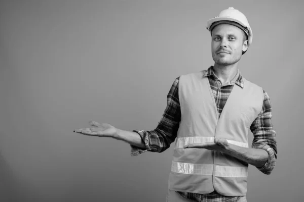 Hombre guapo trabajador de la construcción contra el fondo gris —  Fotos de Stock