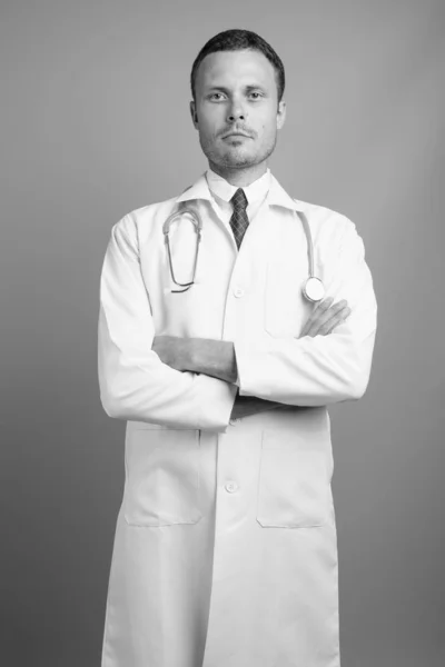 회색빛 배경 과는 대조적으로 잘생긴 의사의 모습 — 스톡 사진