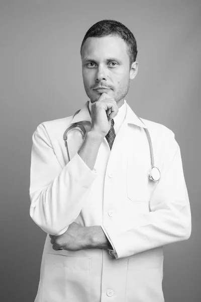 Portrait of handsome man doctor against gray background — Stock Photo, Image