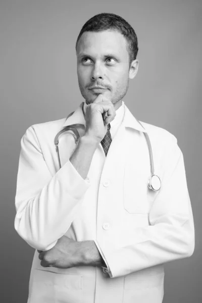 Portrait of handsome man doctor against gray background — Stock Photo, Image