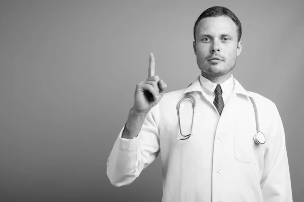 Portrét pohledného muže lékaře na šedém pozadí — Stock fotografie