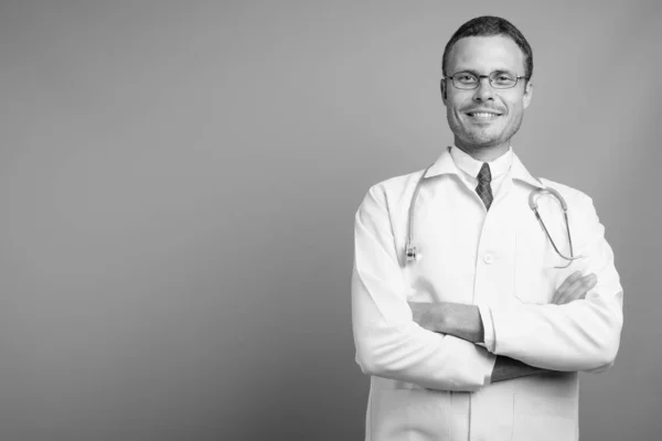 Portrét pohledného muže lékaře na šedém pozadí — Stock fotografie