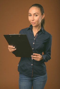 Genç ve güzel iş kadınının çekimleri kahverengi arka planda.