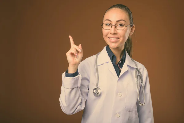 Студийный снимок молодой красивой женщины-врача на коричневом фоне — стоковое фото