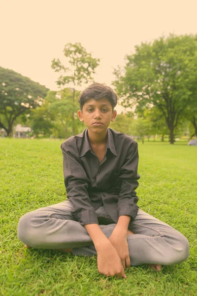 Portrét mladého indického chlapce relaxační v parku — Stock fotografie