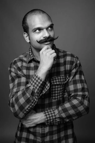 Indian man with mustache against gray background
