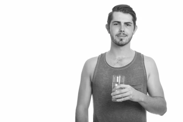 Młody przystojny kaukaski mężczyzna trzyma szklankę wody gotowy na siłowni — Zdjęcie stockowe