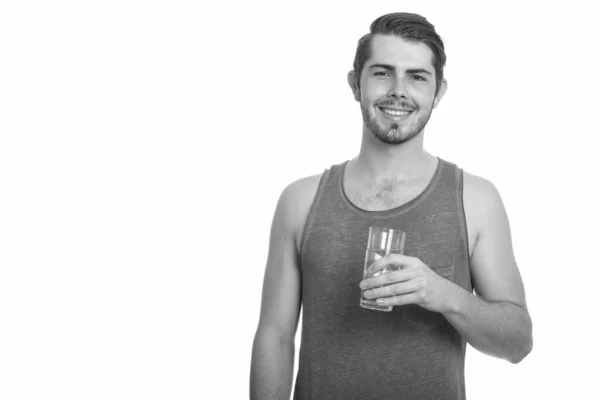 Młody szczęśliwy kaukaski mężczyzna trzyma szklankę wody gotowy na siłowni — Zdjęcie stockowe