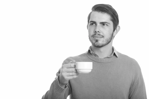 Młody przystojny kaukaski mężczyzna trzyma kubek kawy podczas myślenia — Zdjęcie stockowe