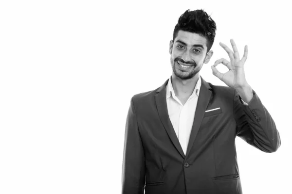 Estúdio tiro de jovem feliz empresário persa sorrindo enquanto dá sinal ok — Fotografia de Stock