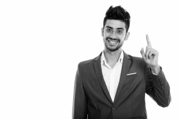 Estúdio tiro de jovem feliz empresário persa sorrindo enquanto apontando o dedo para cima — Fotografia de Stock