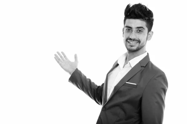 Studio colpo di giovane felice uomo d'affari persiano sorridente mentre mostra qualcosa sul muro — Foto Stock