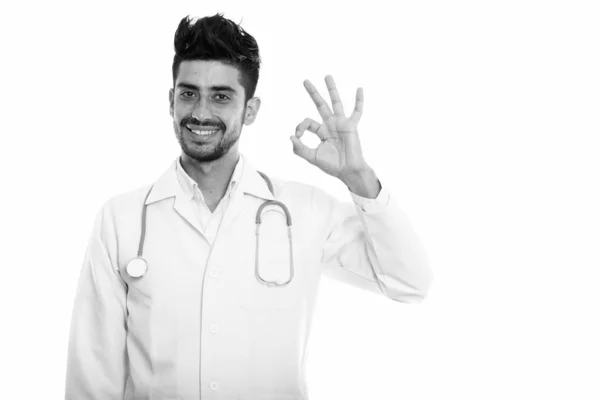 Studio πλάνο της περσικής χαρούμενος νεαρός γιατρός χαμογελώντας ενώ δίνοντας εντάξει σημάδι — Φωτογραφία Αρχείου