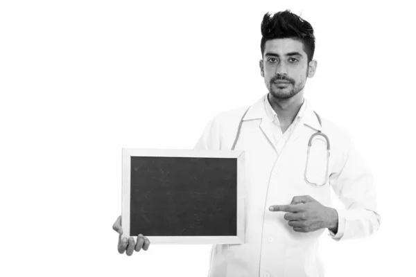 Studio πλάνο της περσικής νεαρός γιατρός κρατώντας και δείχνοντας κενό μαυροπίνακα — Φωτογραφία Αρχείου