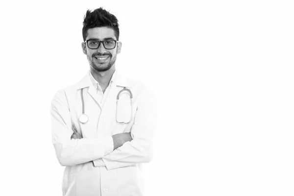 Estúdio tiro de jovem feliz persa homem médico sorrindo enquanto vestindo óculos com os braços cruzados — Fotografia de Stock