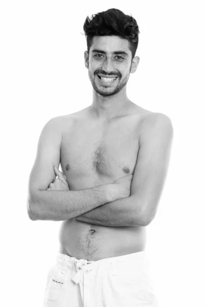 Studio shot of young happy Persian man smiling while standing shirtless with arms crossed — Stock Photo, Image