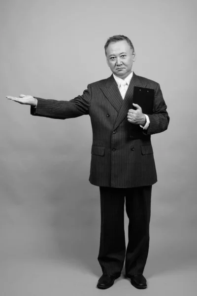 Студийный Снимок Зрелого Азиатского Бизнесмена Держащего Планшет Сером Фоне Черно — стоковое фото