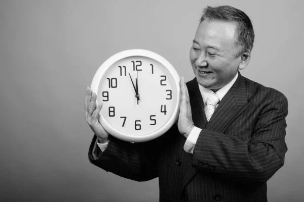 Studio Shot Mature Asian Businessman Holding Wall Clock Gray Background — Fotografia de Stock