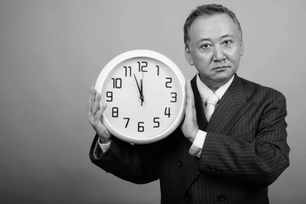 Studio Shot Mature Asian Businessman Holding Wall Clock Gray Background —  Fotos de Stock