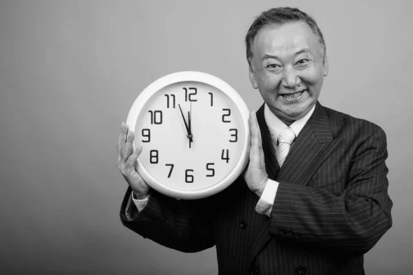 Studio Shot Mature Asian Businessman Holding Wall Clock Gray Background — Stock Photo, Image
