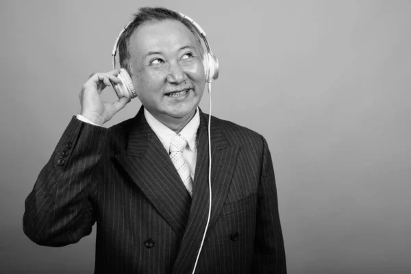 Studio Skott Mogen Asiatisk Affärsman Lyssnar Musik Mot Grå Bakgrund — Stockfoto