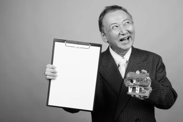 Studio Shot Mature Asian Businessman Holding House Figurine Clipboard Gray — Fotografia de Stock
