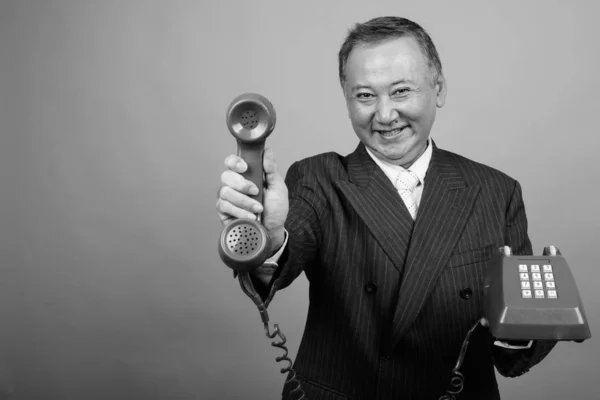 亚洲商人在黑白相间的灰色背景下使用老式电话的演播室照片 — 图库照片